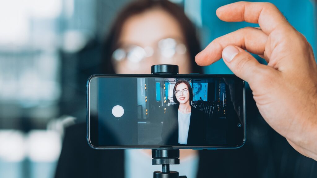 A phone camera recording a woman in a business outfit